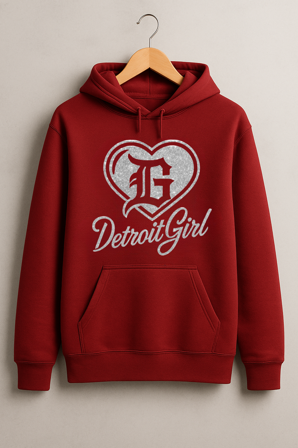 Cardinal red hoodie on hanger featuring silver glitter heart logo with gothic “G” and script text reading Detroit Girl.