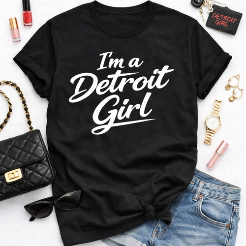Black t-shirt with 'I'm a Detroit Girl' text, paired with denim shorts and accessories on a white background.