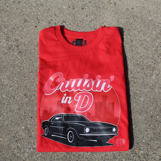 Front view of red unisex T-shirt with “Cruisin’ in the D” graphic black muscle car, Detroit skyline in a circle, and DG heart logo by I’m a Detroit Girl Clothing.