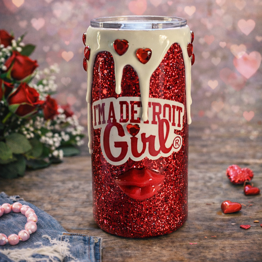 Red glittery tumbler with 'I'm a Detroit Girl' text on a wooden surface with flowers and hearts.
