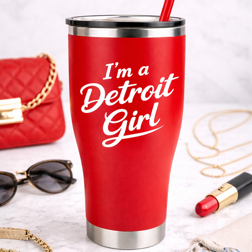 Red tumbler with 'I'm a Detroit Girl' text on a white surface with accessories.
