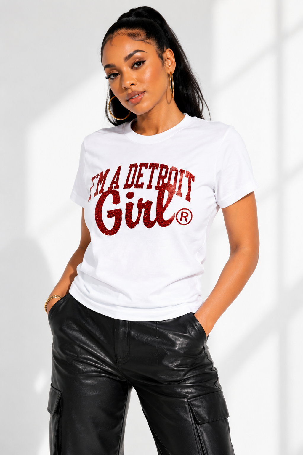 Woman wearing a white t-shirt with 'I'm a Detroit Girl' text on a light gray background