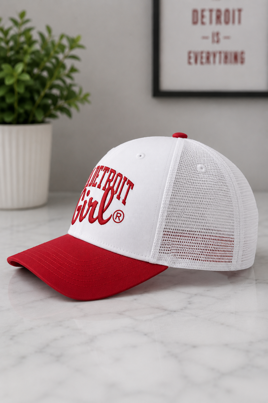 White and red cap with 'Detroit Girl' logo on a marble surface.
